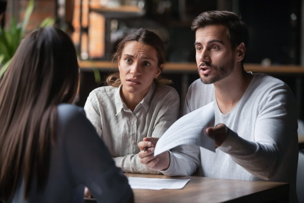 A couple appear distressed as they argue with a woman over a document.