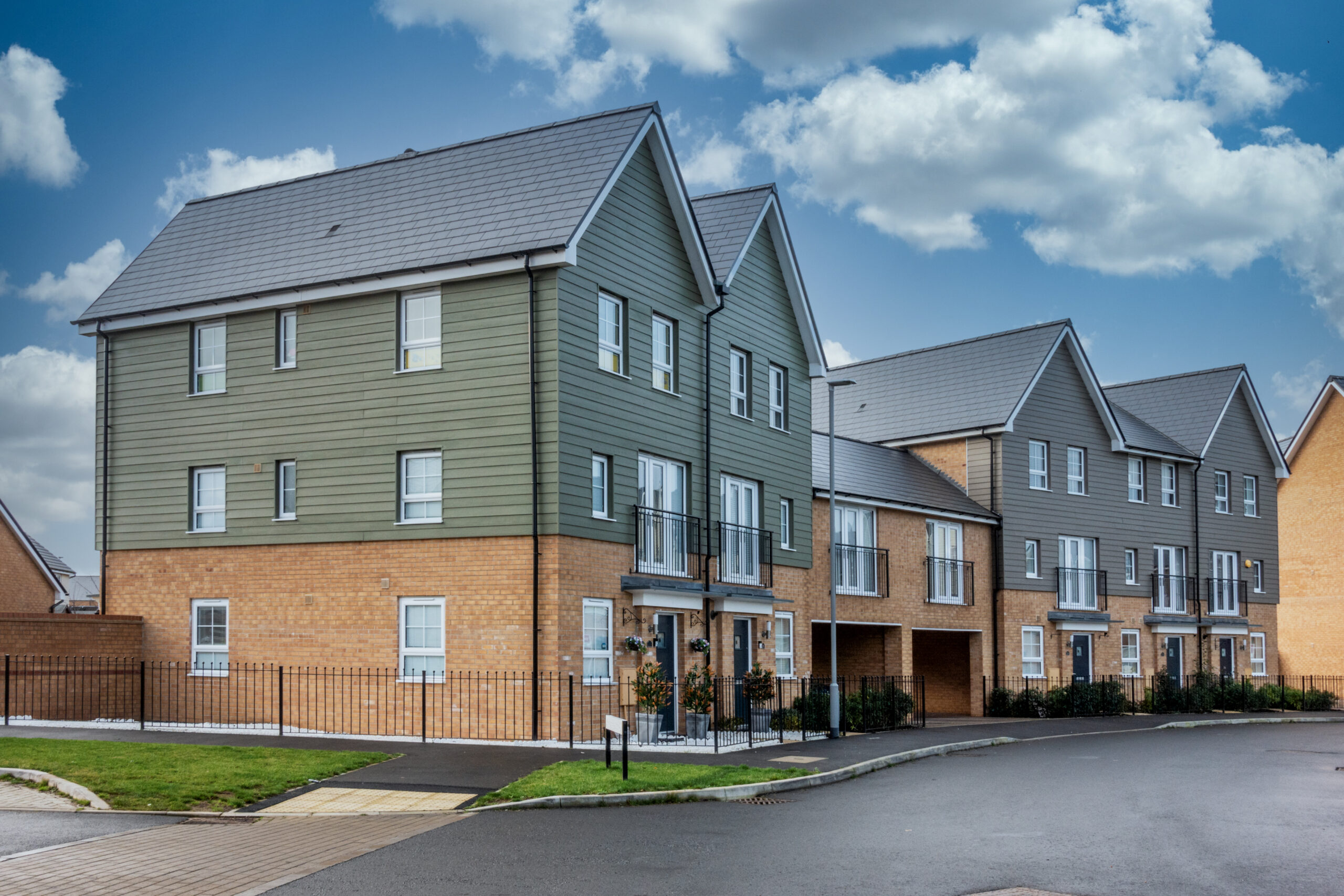 British new-build properties, with three storeys, pictured on a sunny day.