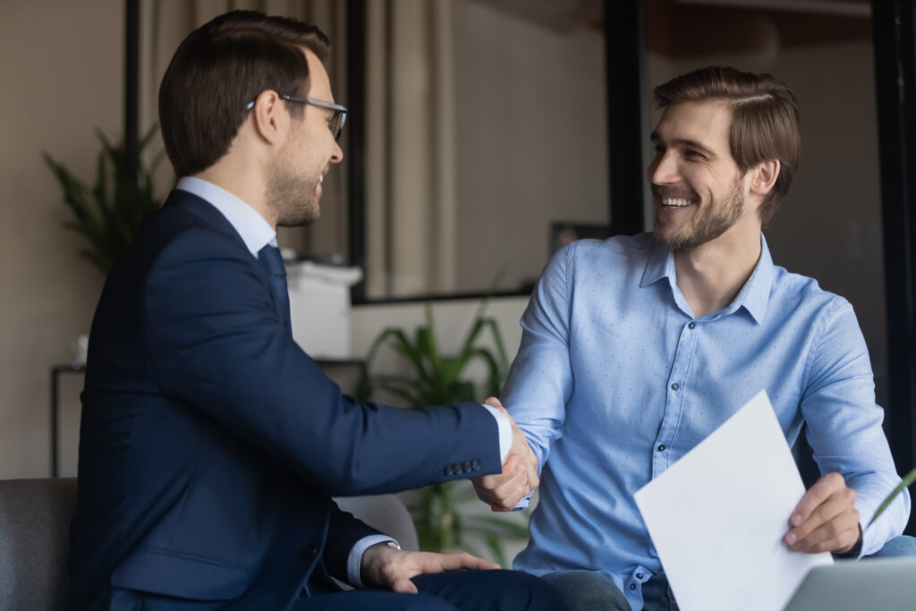 Two smiling men shake hands after resolving a dispute.