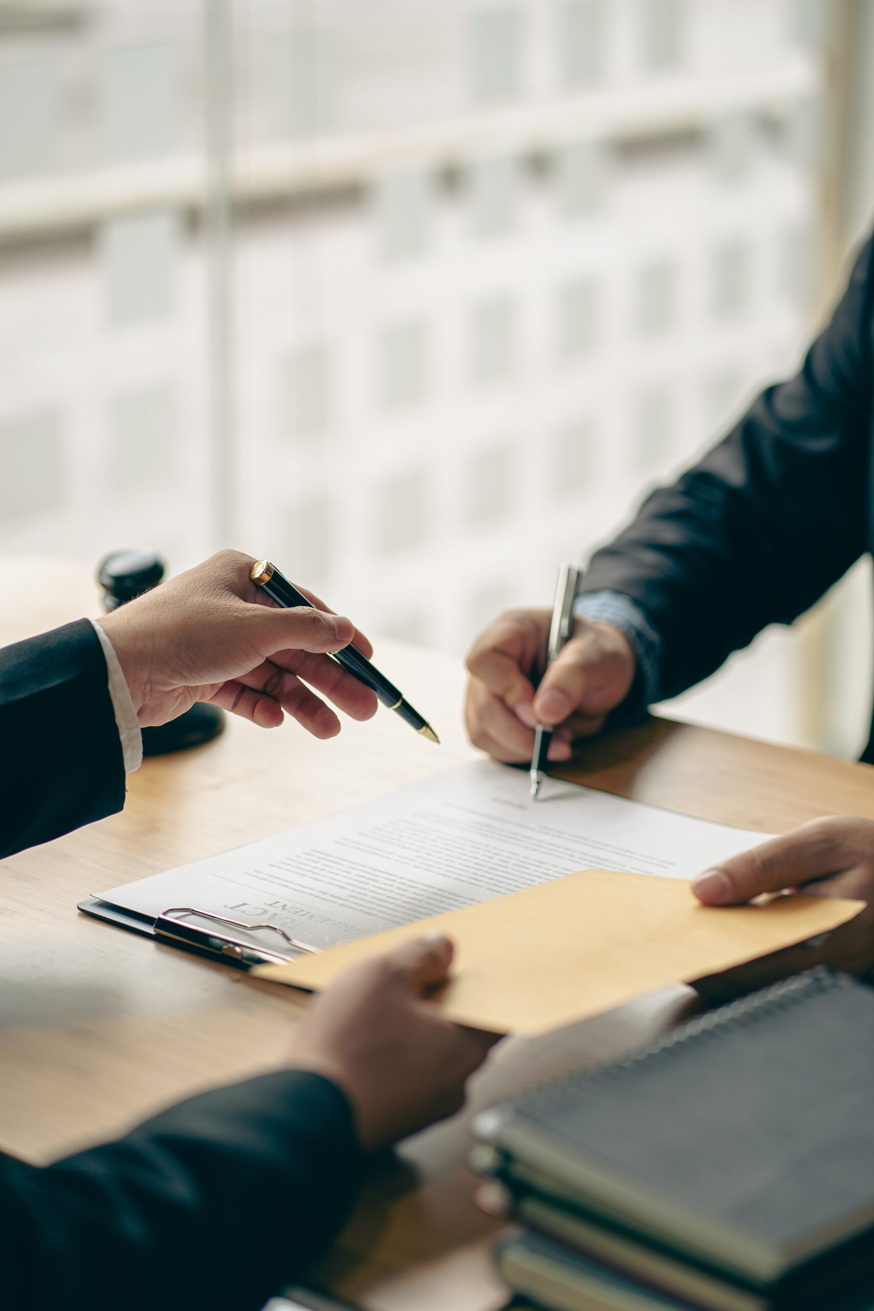 A client sits with a solicitor and signs his Will document.