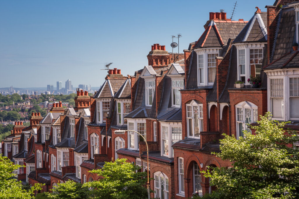 A row of traditional terraced houses on a hill that overlooks a city, pictured on a sunny day.