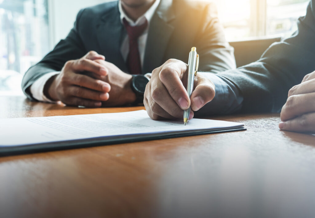 A closeup of a businessman signing a document in a professional meeting.