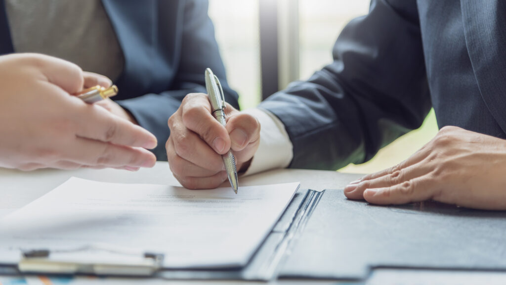 Business partners sit at a table and sign a contract to purchase commercial property.