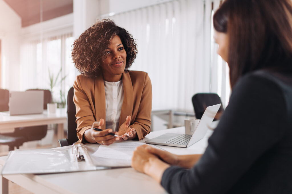 A recruiter interviews a young woman in a modern office.