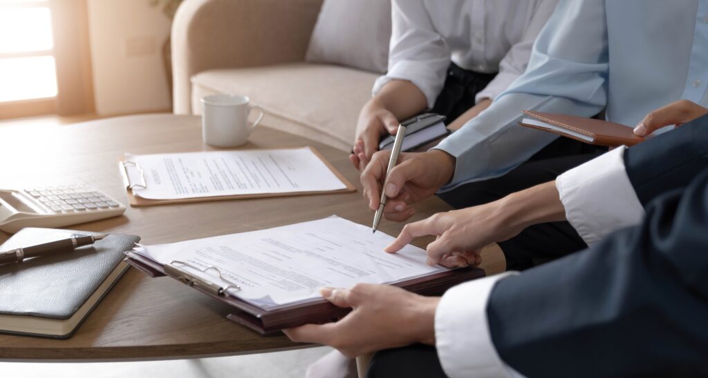 A closeup of a solicitor directing a client on where to sign a document.