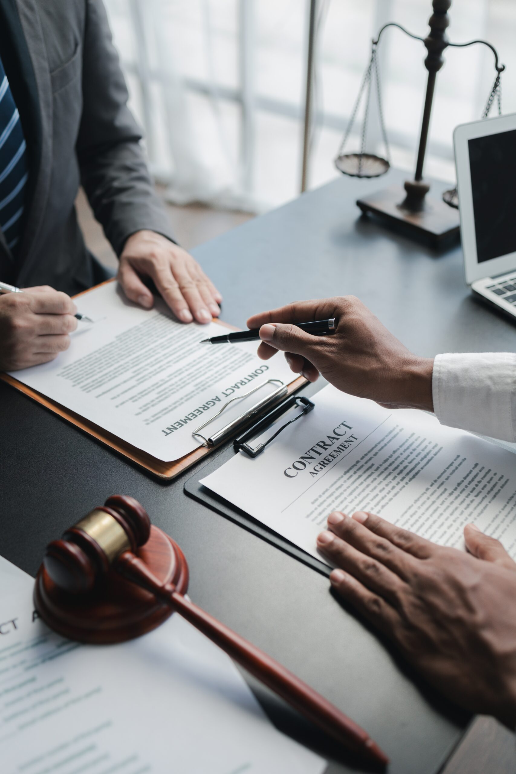 A solicitor sits at a desk with a client and goes through an employment contract.