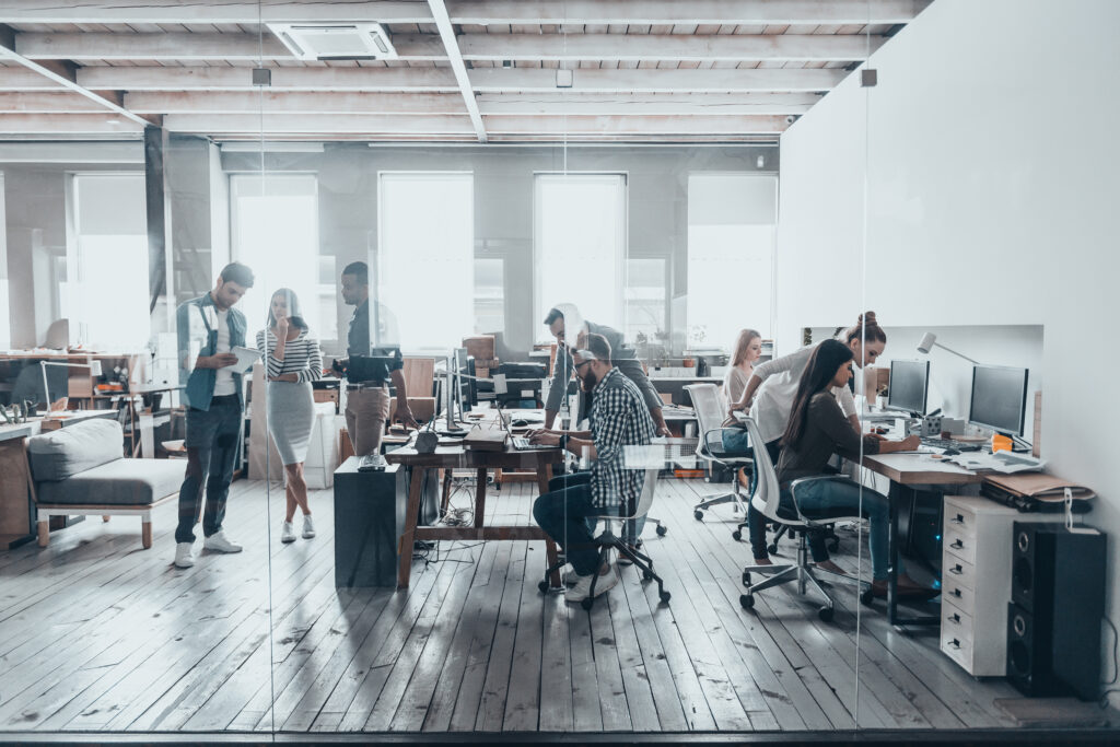 A wide view image of a modern office with young business people working at their desks.