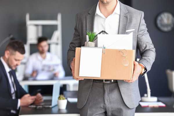 A dismissed male employee walks out of the office with a box of his personal possessions.