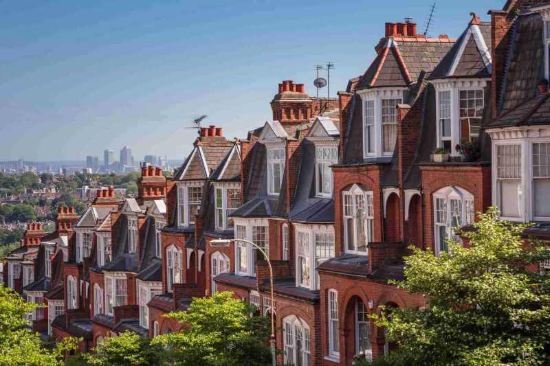 A row of traditional terraced houses on a hill that overlooks a city, pictured on a sunny day.