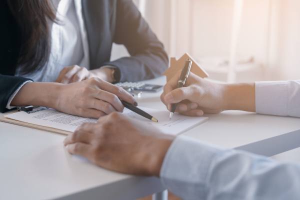 A female lettings manager directs a male client on where to sign a rental contract.